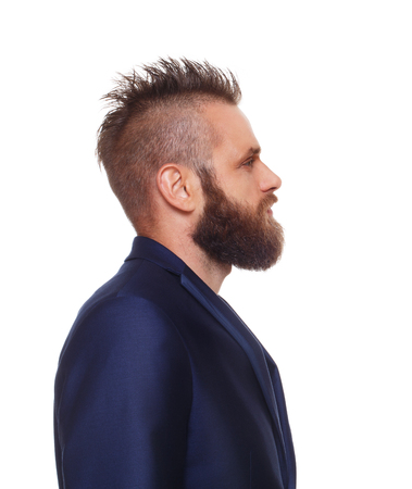 Young bearded man profile isolated at white background. Close up side view portrait of guy with beard. Boy style, trendy hipster with cool hairstyle in blue suit. Modern businessman.の写真素材