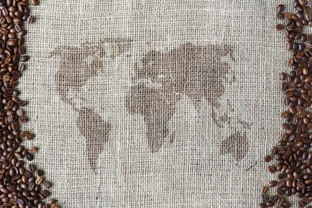 World map at burlap texture with coffee beans border. Sack cloth background. Brown natural sackcloth canvas. Seeds at hessian textileの写真素材