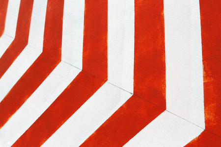Red and white stripes closeup background. Painted concrete wall, looking like road bend traffic sign. Contrast bright lines surface.の写真素材