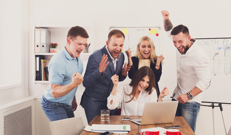Happy business people celebrate success looking at laptop screen in the office. Successful corporate...