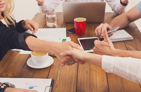 Business female handshake at office corporate meeting, contract conclusion and successful agreement concept. Closeup of businesswoman and other woman hands meet at wooden table background.の写真素材
