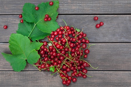 Fresh ripe red currants heap on rustic wood background. Natural organic berries with green leaves...