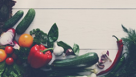 Bottom line border on white wood for menu or recipe, fresh organic vegetables and greens background. Healthy natural food on wooden table with copy space. Cooking ingredients top view, soft toningの写真素材