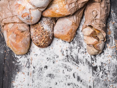 Baking and cooking concept background. Border of different bread sorts, wrapped in craft paper top...
