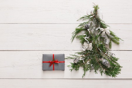 Christmas background. Gift boxes on fir tree branches at white wood. Stylish modern presents in gray paper decorated with satin ribbon bows. Winter holidays concept, top view, copy space