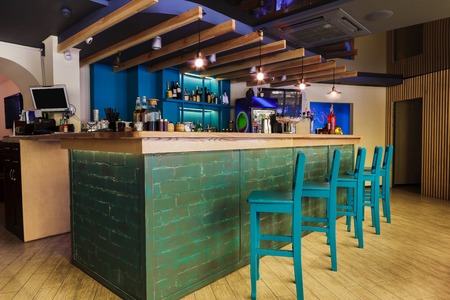 Modern restaurant or cafe interior. Public place interior design, bright blue wooden chairs, large bar counter desk. Morning light, nobody indoors.の写真素材