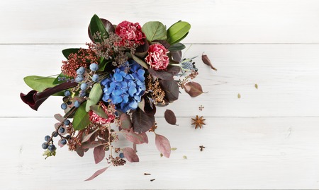 Beautiful autumn bouquet composition of dried roses and meadow flowers with leaves, floral fall background. Floristic art decoration closeup, top view with copy spaceの写真素材