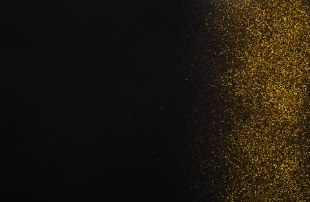 Golden glitter sand texture border on black, abstract background with copy space. Yellow dusty shimmer decoration, shiny and sparkling. Holidays and glamour concept.の写真素材