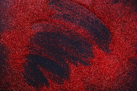 Red glitter sand texture spread on black, abstract background. Red dusty shimmer decoration, shiny and sparkling. Holidays and glamour concept.の写真素材