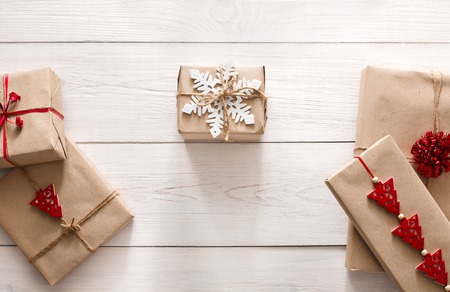Christmas holiday handmade presents in craft paper with twine ribbon background. Kraft Boxes with bows and snowflakes on white wooden table, top view.の写真素材