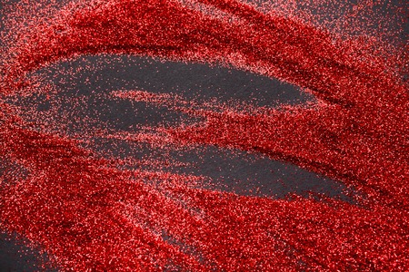 Red glitter sand texture spread on black, abstract background. Red dusty shimmer decoration, shiny and sparkling. Holidays and glamour concept.の写真素材