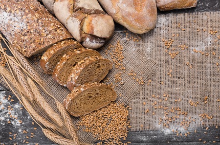 Plenty of sliced rye bread background. Bakery and grocery concept. Fresh, healthy whole grain sliced sorts of rye and white loaves, sprinkled flour on sackcloth with copy spaceの写真素材