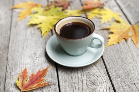 Autumn leaves and espresso composition. Blue cup of black coffee, at weathered rustic wood background with copy space. Fall hot drinks conceptの写真素材