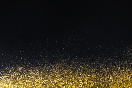 Golden glitter sand texture border on black, abstract background with copy space. Yellow dusty shimmer decoration, shiny and sparkling. Holidays and glamour concept.の写真素材