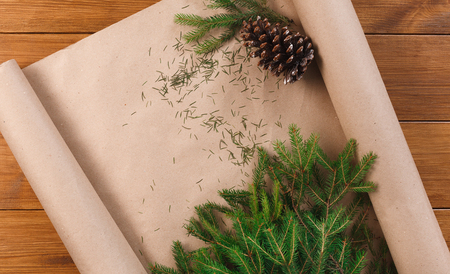 Prepare for christmas eve or other winter holidays. Xmas decorations, fir tree and garlands concept background, top view on wood. Present packaging craft paper and pine conesの写真素材