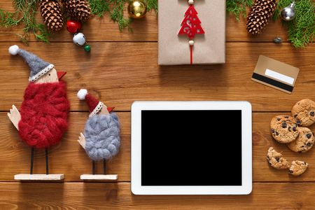Christmas online shopping background. Tablet screen with copy space top view on wood, credit card, xmas toys ans presents. Electronic devices, internet commerce on winter holidays conceptの写真素材