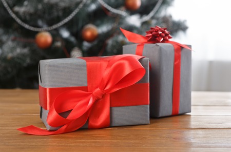Wrapped present boxes with red satin ribbon on table closeup and beautiful decorated christmas tree...