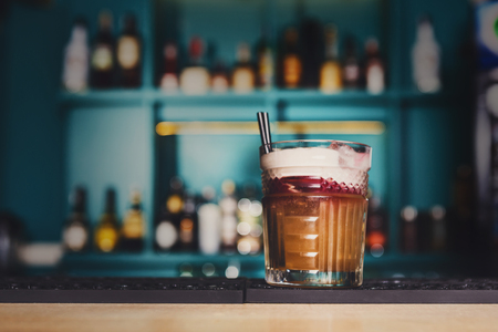 Closeup of creamy sweet exotic party alcohol cocktail in restaurant at bar background. Glass on bar table, refreshing drink with straw. Cream soda or other.の写真素材