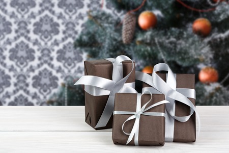 Wrapped present boxes on wood closeup and beautiful decorated christmas tree with ornaments and...