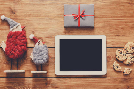 Christmas online shopping background. Tablet screen with copy space top view on wood, credit card, xmas toys and presents. Electronic devices, internet commerce on winter holidays conceptの写真素材