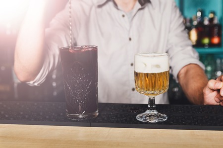 Barman mix exotic sweet cocktails in restaurant. Professional bartender's hands make drinks in night club bar. Selective focus on glassesの写真素材
