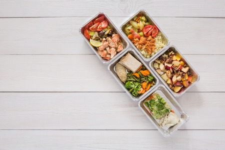 Healthy food take away in boxes, top view at wood