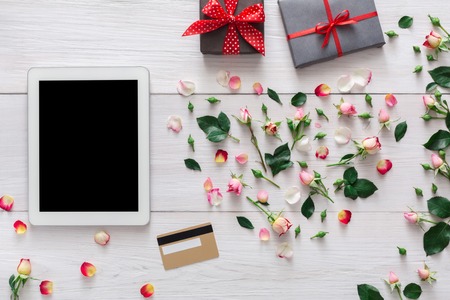 Valentine day internet sales concept, online shopping holiday background. Tablet screen with copy space on white wood with rose flowers heart and credit card, top view. Advertising mockupの写真素材