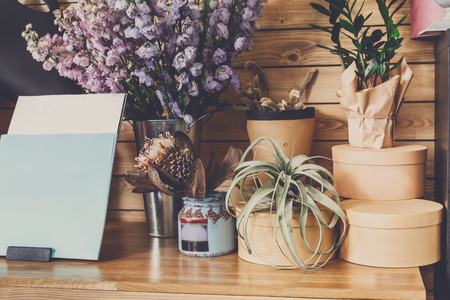 Small business. Modern flower shop interior. Floral design studio, decorations and arrangements. Flowers delivery service and sale of home plants in pots, wooden showcase, filtered imageの写真素材