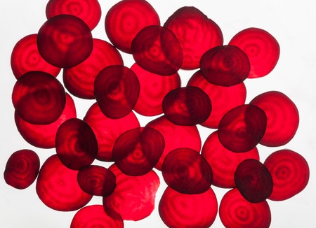 Backlit of red beetroot round slices on white, pattern for textured background. Abstract art composition of fresh organic vegetablesの写真素材