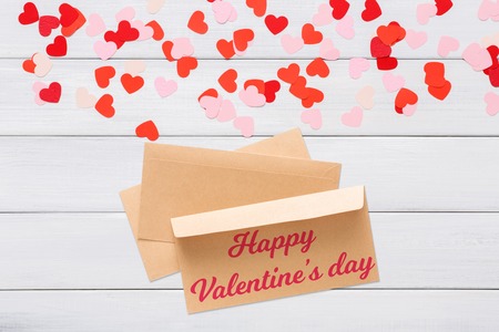 Valentine day letter. Envelope from craft paper with red heart on it, on white wood background....