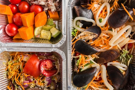 Healthy food background. Take away of natural organic meals in foil boxes. Fitness nutrition, mussels seafood, cheese, meat and salads. Top view, flat lay. Restaurant dishes deliveryの写真素材