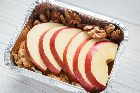 Healthy snack or lunch. Natural food in foil box, diet concept. Apple dessert with walnutsの写真素材