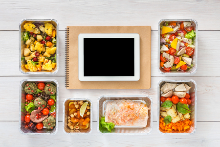 Healthy restaurant food internet online order background. Eating right. Fresh diet daily meals delivery. Nutrition with vegetables, meat and fruits in foil box. Top view, flat lay on wood, copy spaceの写真素材