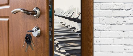Opened door handle closeup to modern gym interior with equipment. Entrance to fitness club with row of treadmills for fitness cardio training. Welcome to sport, healthy lifestyle conceptの写真素材