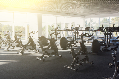 Modern gym interior with equipment. Fitness club with row of training exercise bikes, backlight. Healthy lifestyle concept. Filteredの写真素材