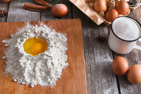 Baking concept. Flour and eggs on rustic wooden table, cooking ingredients. Making doughの写真素材