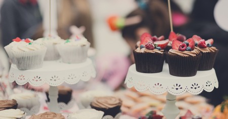 Beautiful cupcakes with berries and chocolate cream on banquet table. Sweet cakes. Wedding catering, dessert served outdoorsの写真素材
