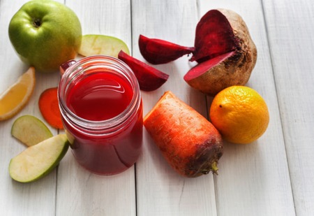 Detox cleanse drink, vegetable smoothie ingredients. Natural, organic healthy juice in glass jar for weight loss diet or fasting day. Beetroot, apple, carrot and lemon mix on white wood, copy spaceの写真素材
