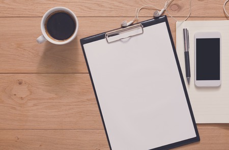 Notepad, diary, mobile phone and espresso coffee. Office or students devices on modern wooden desk. Working table top view. Education or list background with copy space on paper sheetの写真素材