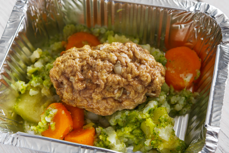 Healthy lunch foil container closeup. Diet nutrition in foil boxes. Steamed minced meat cutlet with vegetablesの写真素材