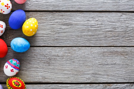 Easter eggs on wood background. Colorful handmade painted eggs on rustic table top view with copy...