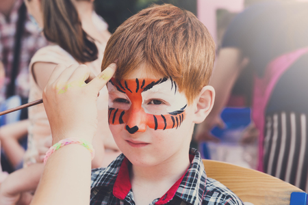 Child with tiger face art painting. Children holiday, birthday party entertainment.の写真素材