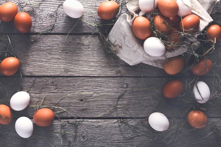 Fresh eggs background on rustic wood, top view, vintage filter