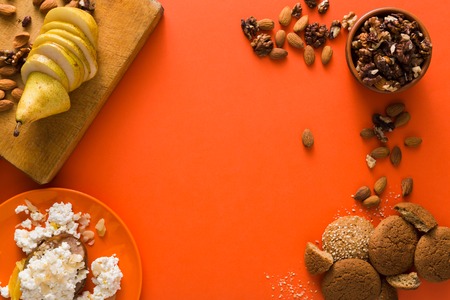 Healthy breakfast, dieting and detox concept - fresh cottage cheese on plate, bowl with nuts and wood board with fruit on bright background. Still life, flat lay, top view, copy spaceの写真素材