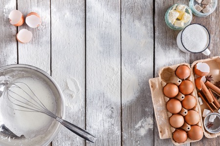 Baking background. Cooking ingredients and utencils for dough and pastry on sprinkled with flour rustic wood. Top view with copy space, mockup for menu, recipe or culinary classes.の写真素材