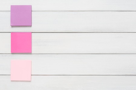 Stationery office and school supply concept - flat lay of colorful sticky notes on white rustic wooden board background, top view with copy space on paper, nobody, objectsの写真素材