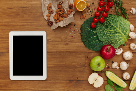 Healthy food, grocery online shopping, copy space on tablet screen. Fresh organic vegetables and fruits on wood table, top view, flat layの写真素材