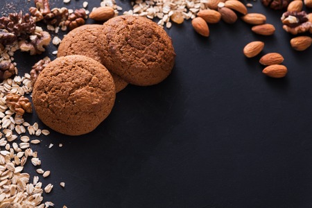 Healthy oat cookies made of wholegrain oat and nuts on dark table background, free copy space. Flat lay, mockup, template, objects, nobodyの写真素材