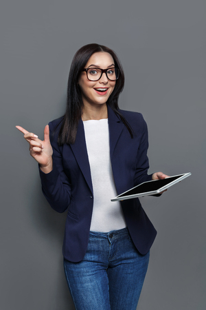 Smart solutions. Beautiful business woman at gray studio background with tablet has an ideaの写真素材