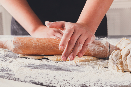 Baking concept. Hands roll dough on black background. Baker cooking pastryの写真素材